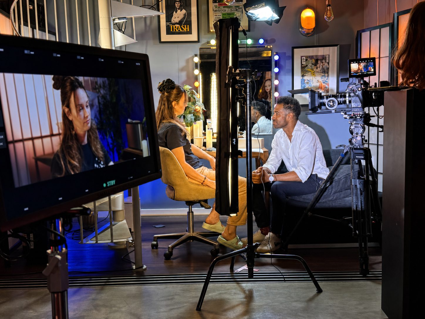Dean Francis in conversation with a student at the studio vanity mirror between takes