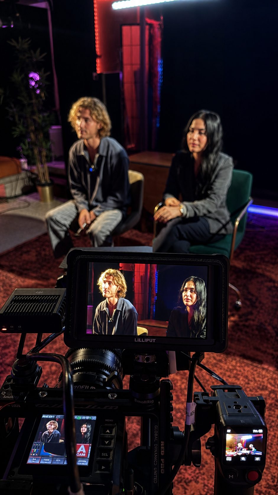 Two students in soft focus behind a RED cinema camera and Lilliput monitor on set